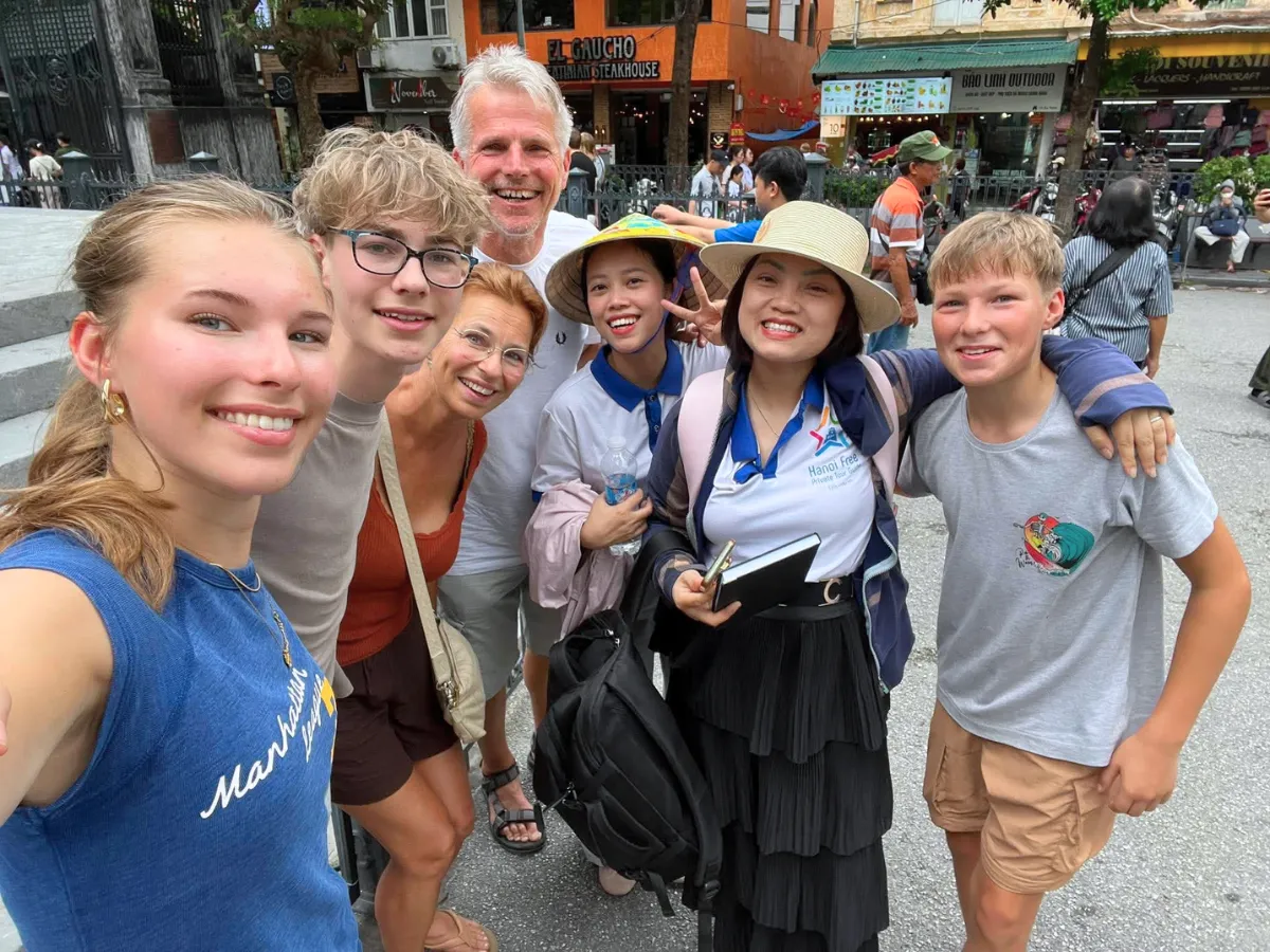 A local guide and guests walking a narrow street in the Hanoi Old Quarter