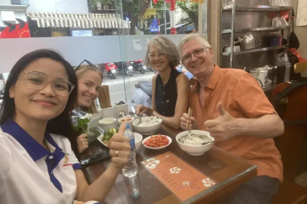 Guests eating street food with a local guide in Hanoi